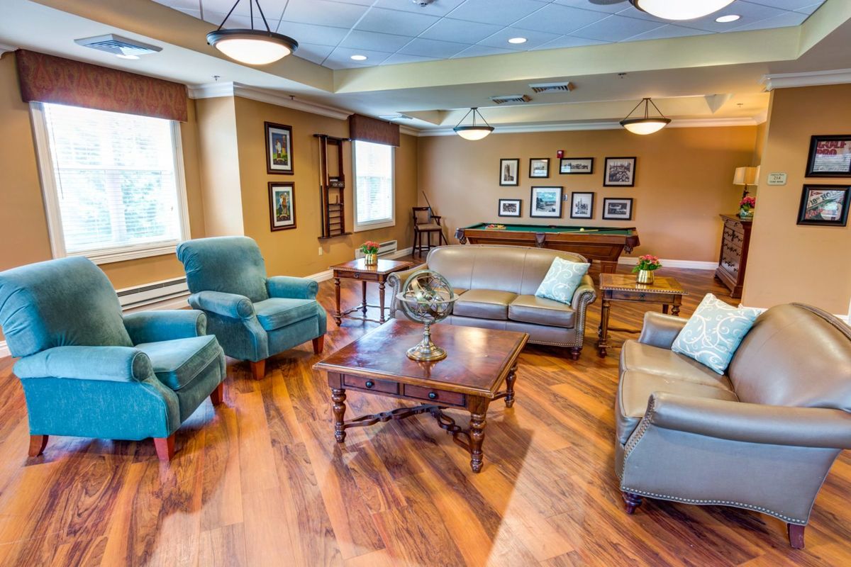A cozy living room with comfortable seating, hardwood floors, and decorative artwork on the walls.