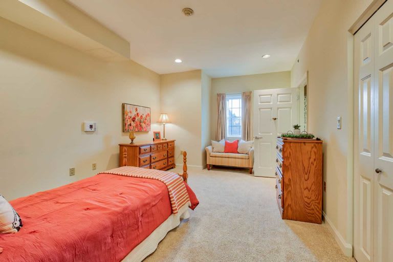 A cozy bedroom with a single bed, dresser, and small sofa.