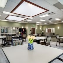 A modern dining area with tables and chairs, featuring a vase of flowers as a centerpiece.