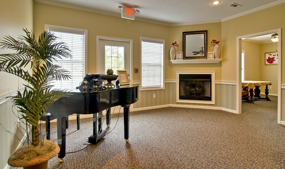 A cozy living room featuring a grand piano and a fireplace.