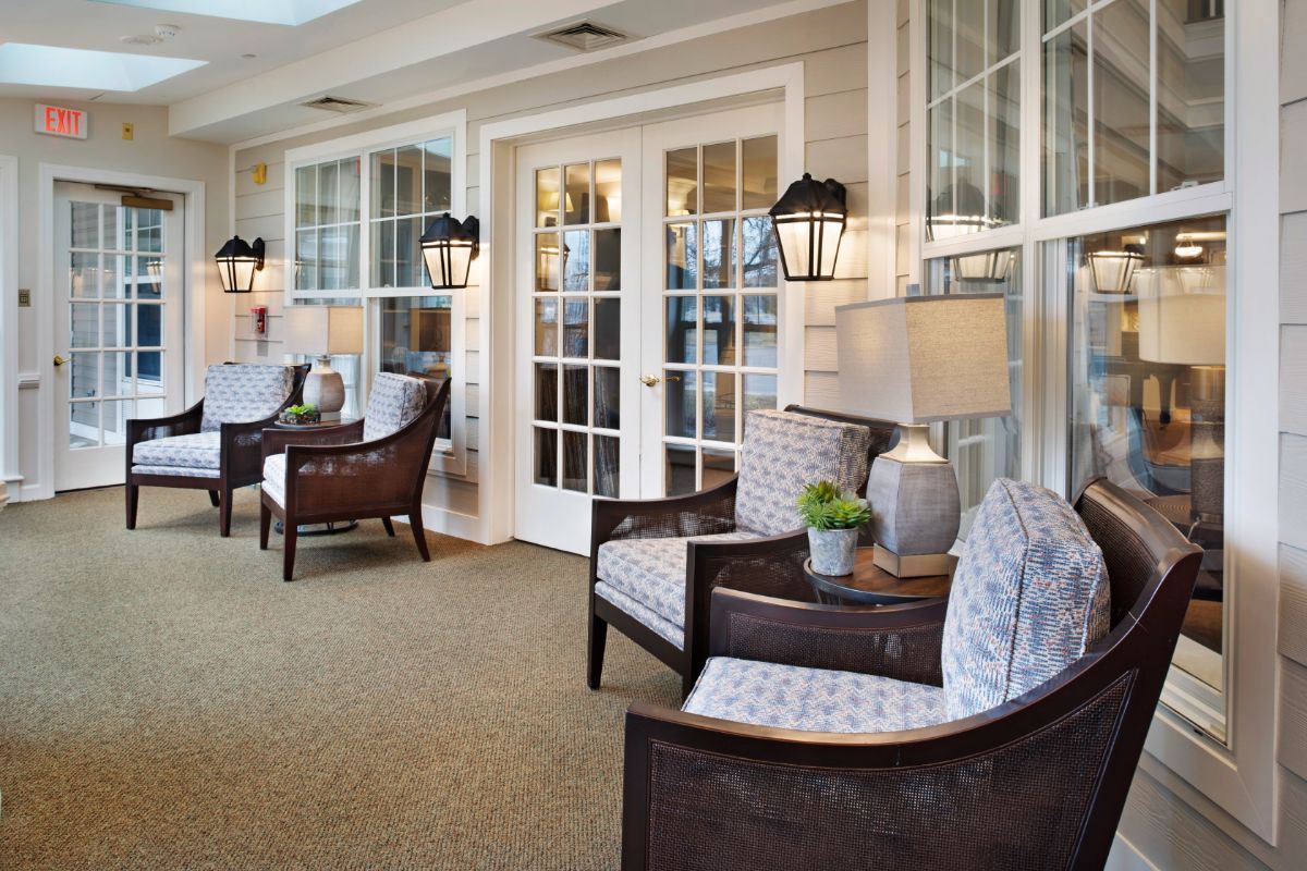 A cozy sunroom with comfortable armchairs, elegant lamps, and large windows.
