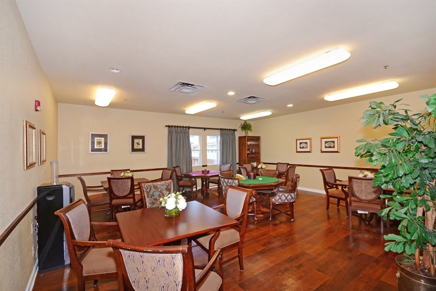 An interior view of a dining room with multiple tables and chairs, decorated with wall art and bright lighting.