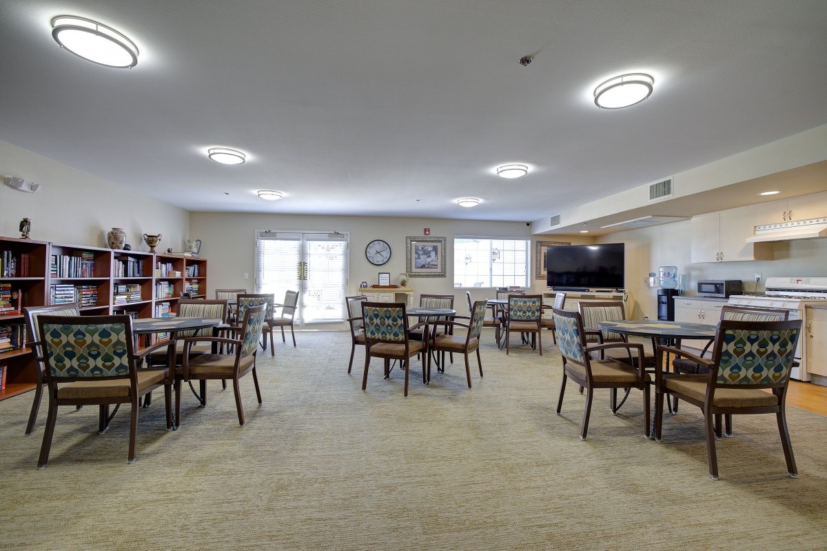 Spacious community dining area with tables, chairs, and library shelves.