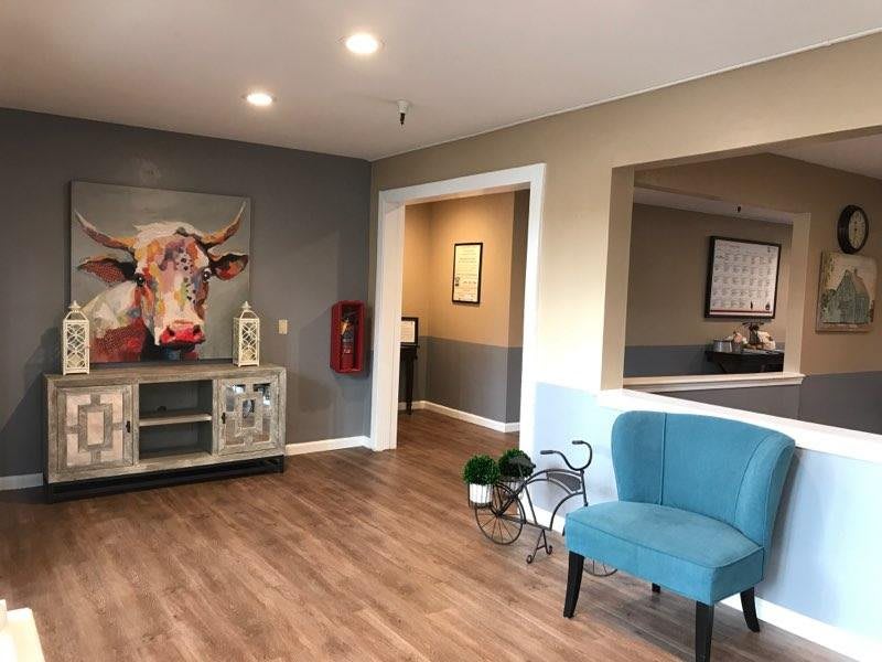 A modern waiting area featuring a blue chair, decorative art, and wood flooring.