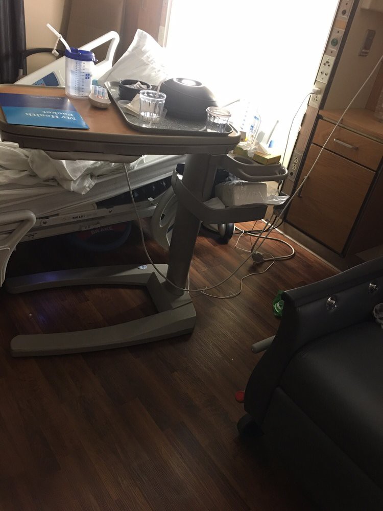 A hospital room with a bed, medical equipment, and furniture.