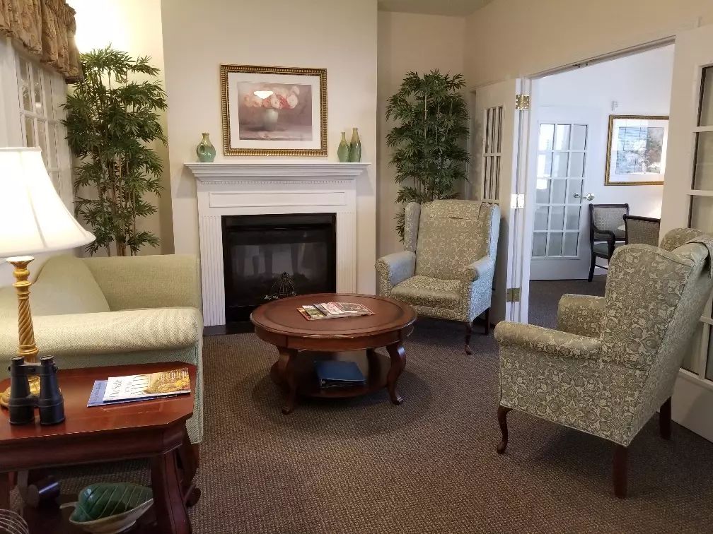 A cozy living room with a fireplace, comfortable seating, and decorative plants.