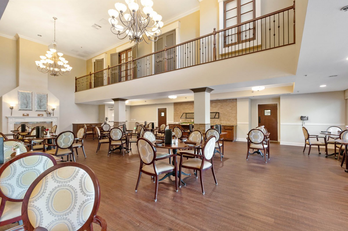 A spacious and elegant dining area with chandeliers and wooden flooring.
