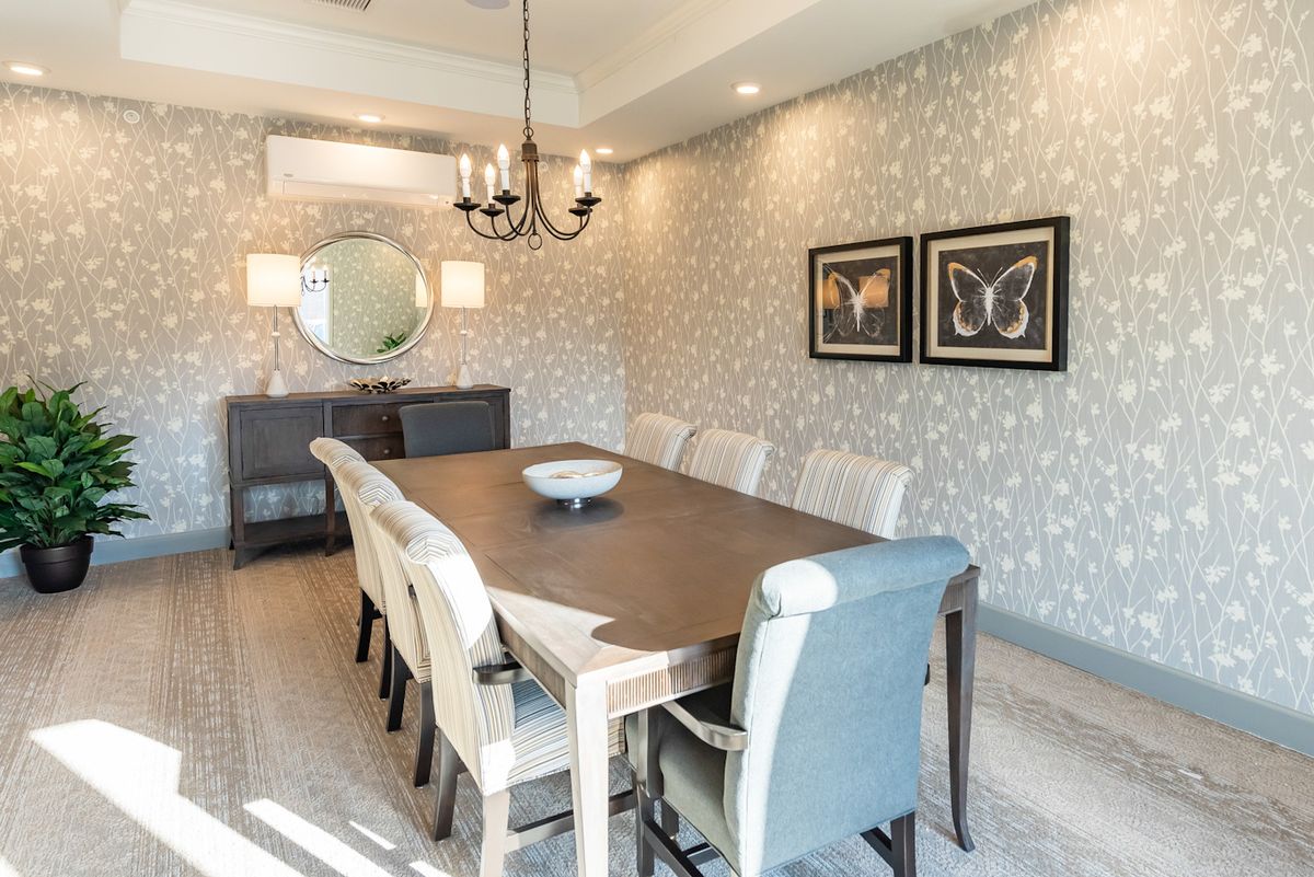 A stylish dining room with a long table, upholstered chairs, and elegant decor.