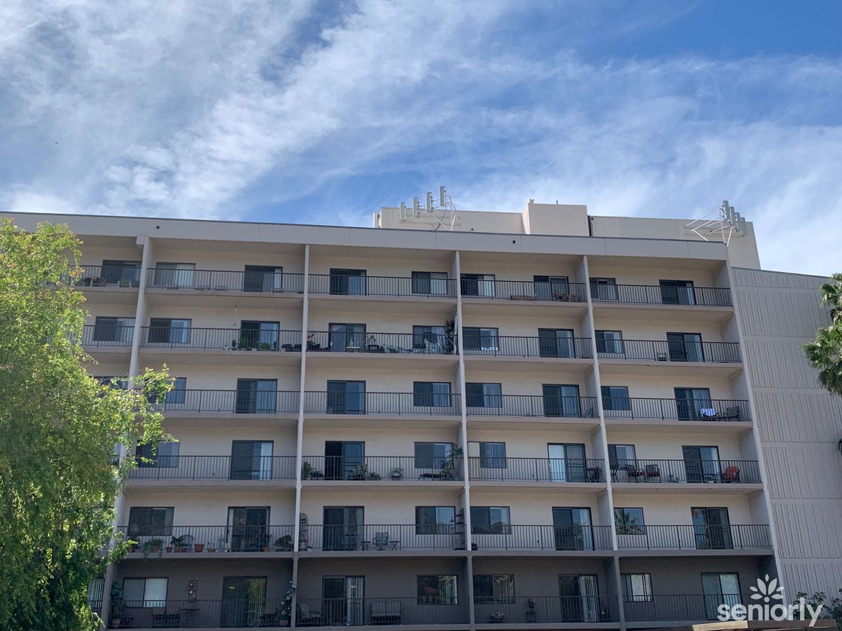 A multi-story apartment building with balconies under a partly cloudy sky.