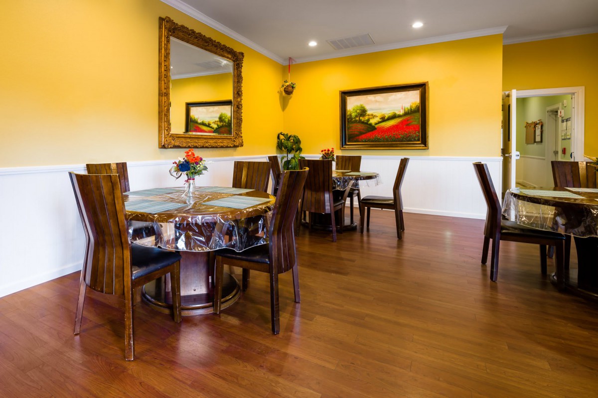 A cozy dining area with wooden flooring, yellow walls, and elegant furniture.