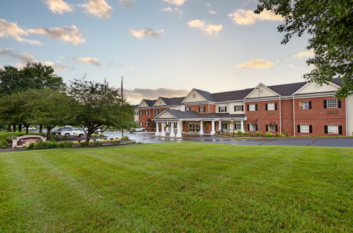 A large brick building with a well-maintained grass lawn under a partly cloudy sky.