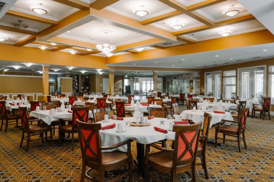 An elegantly set dining room with multiple tables and chairs arranged neatly.