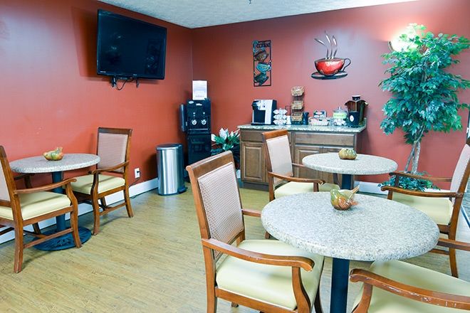 A cozy break room featuring a coffee station, several tables with chairs, a television mounted on the wall, and a water cooler.