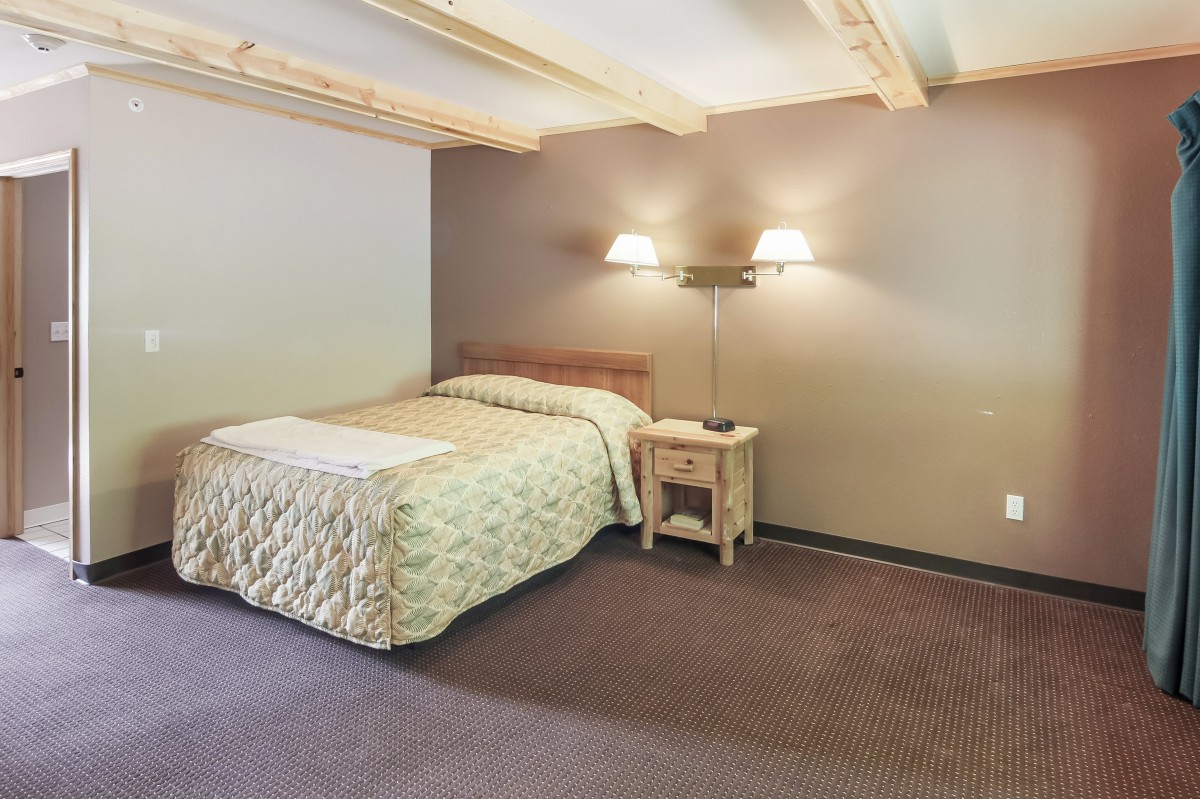 A cozy bedroom with a bed, nightstand, and wall-mounted lamps.