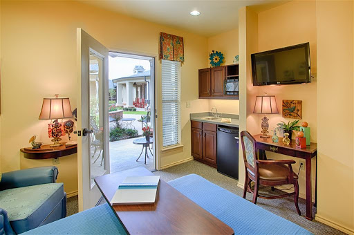 A cozy living area with a kitchenette, featuring warm yellow walls and ample natural light.