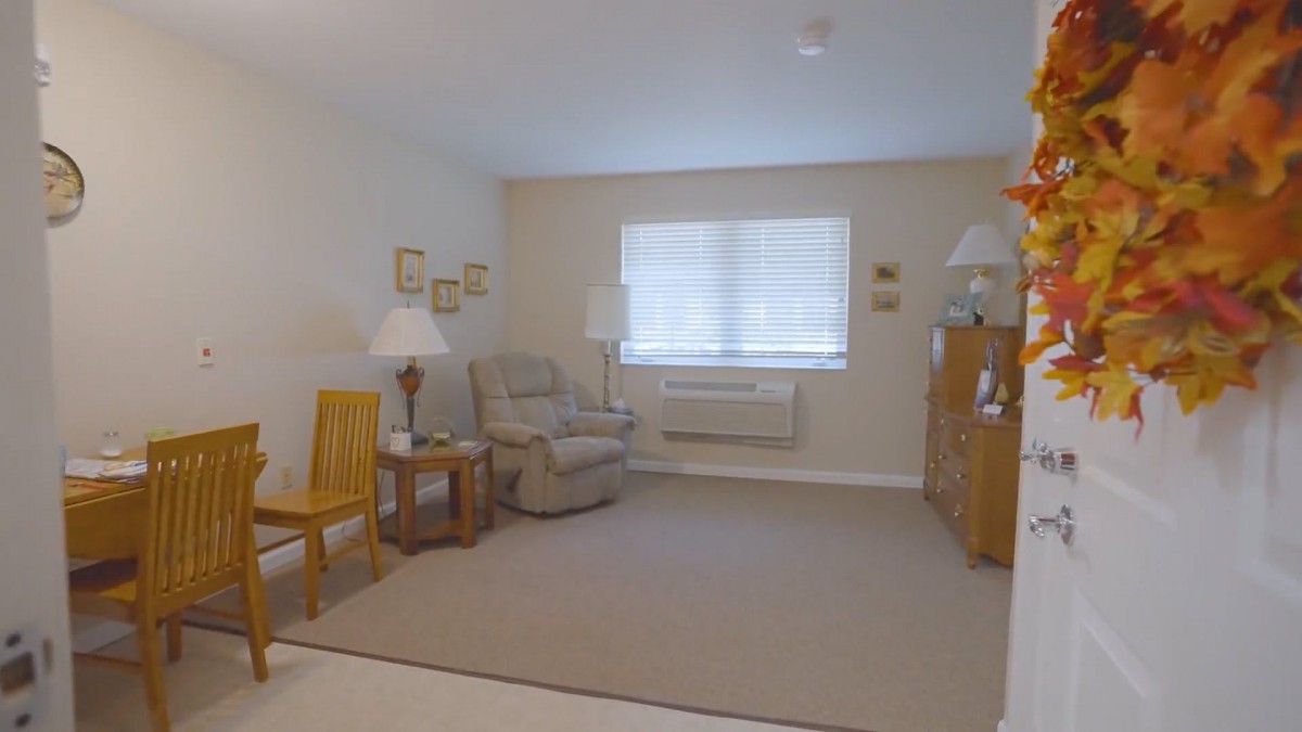 A cozy living room with simple furnishings, including a chair, table, and lamps.