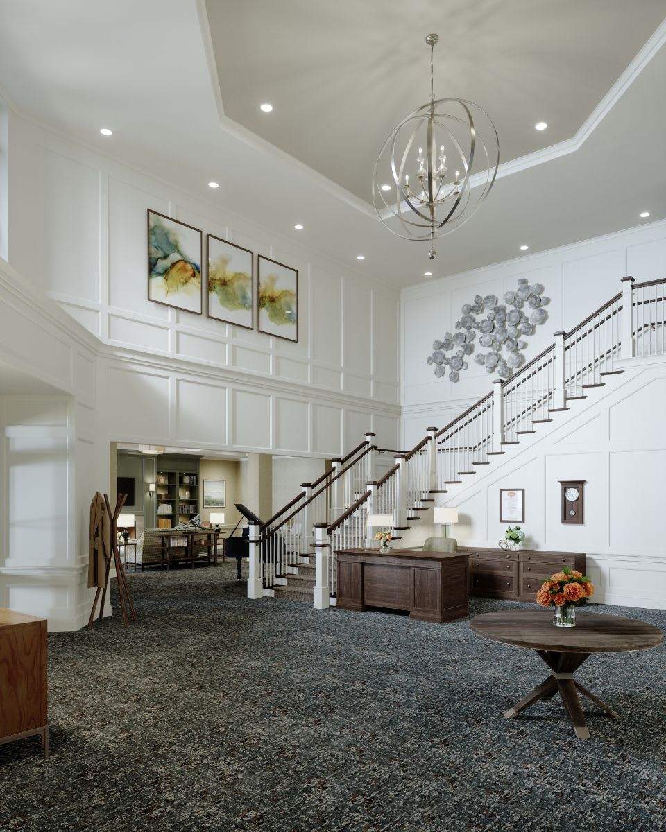 A spacious and elegantly designed foyer featuring a grand staircase, chandelier, and artwork on the walls.