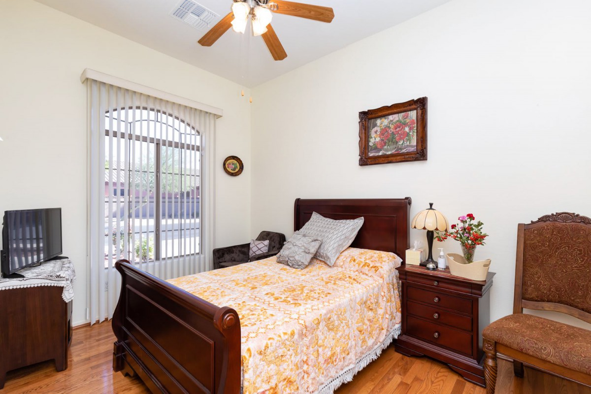 A cozy bedroom with a wooden bed, nightstand, and a ceiling fan.