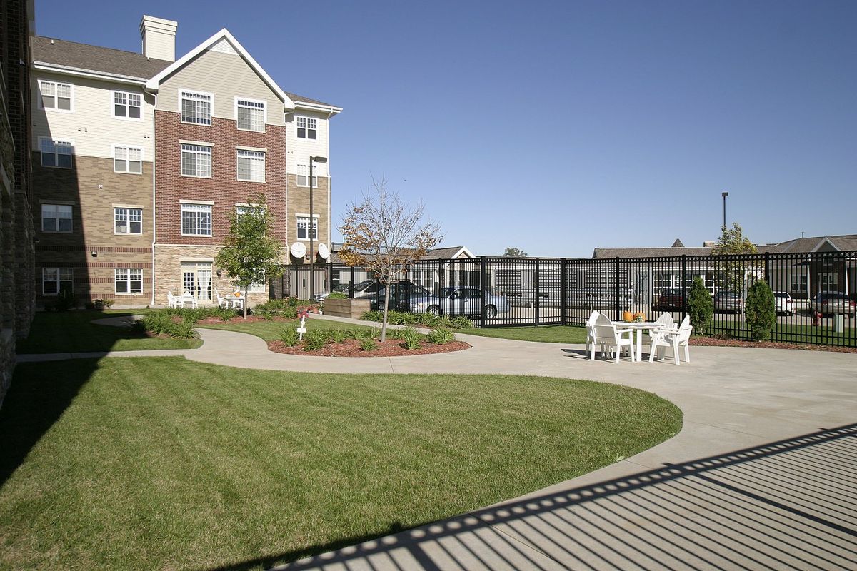 An outdoor view of a residential building with a garden and seating area.