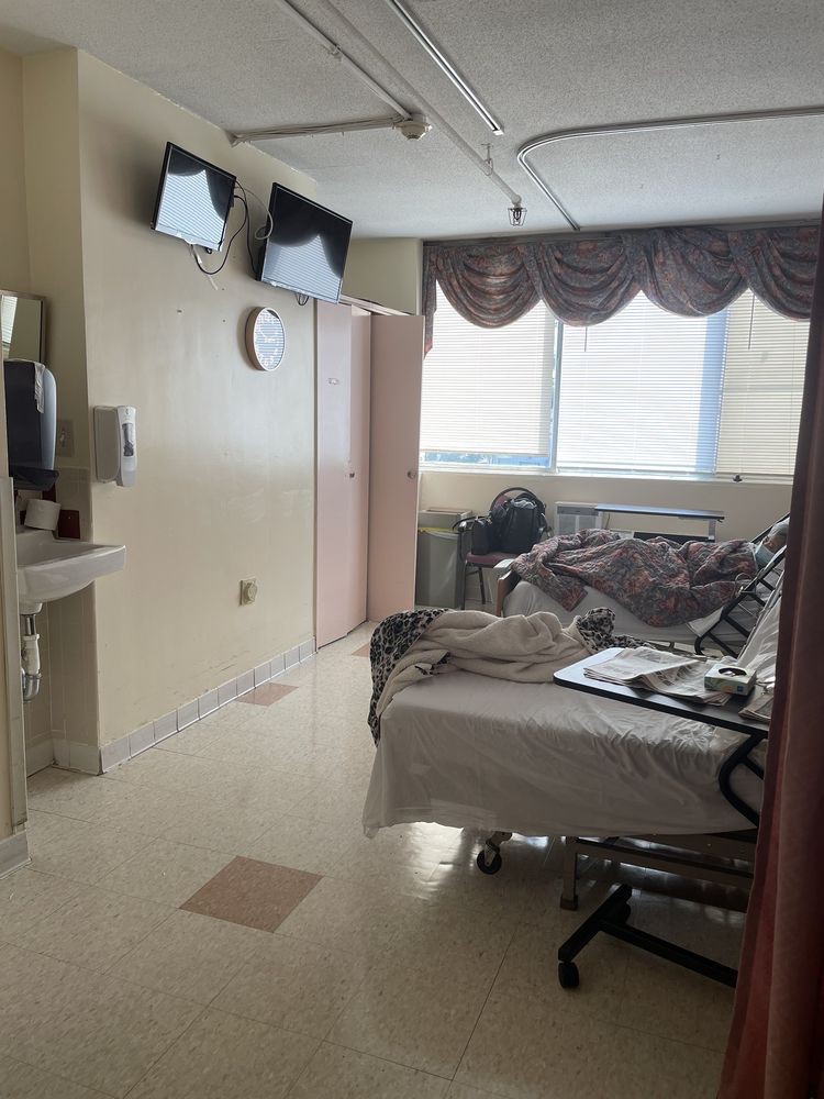 A hospital room with a bed, medical equipment, and a television.