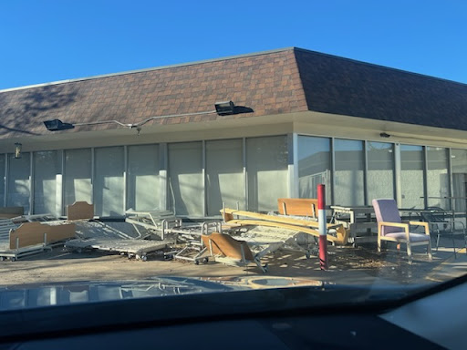 An abandoned building surrounded by scattered debris and furniture.