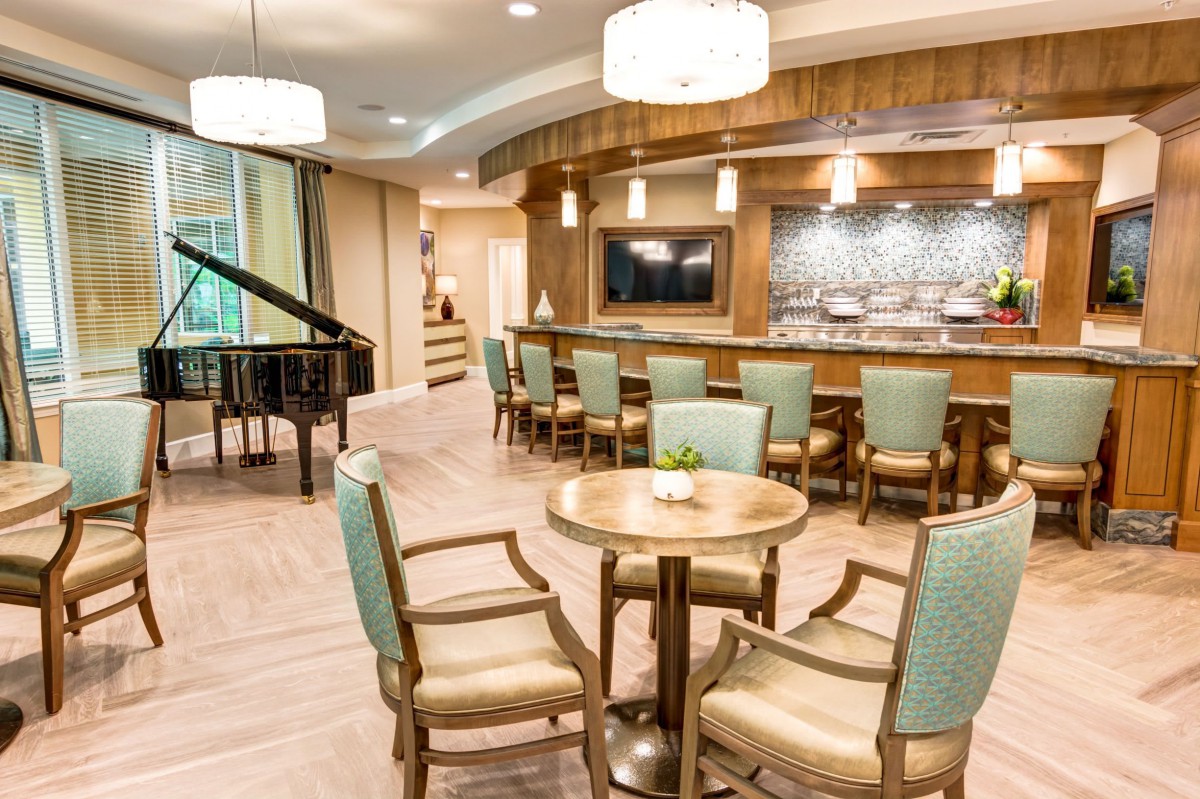 A modern lounge area featuring a bar and a grand piano, surrounded by elegant seating and stylish lighting.