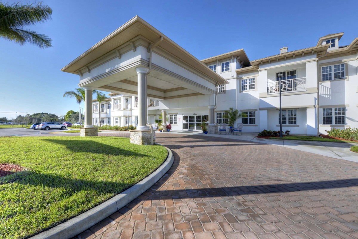 A modern residential building with a paved driveway and landscaped surroundings.