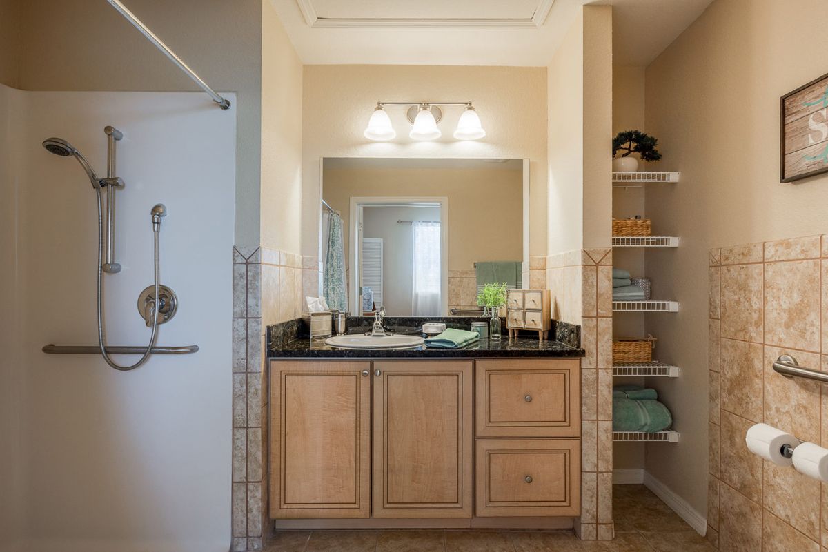 A well-organized bathroom with a sink and mirror, featuring wooden cabinets and open shelving.