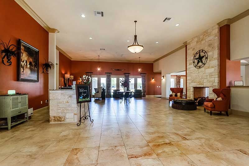 A spacious and elegant lobby with a chandelier and fireplace, featuring tile flooring.