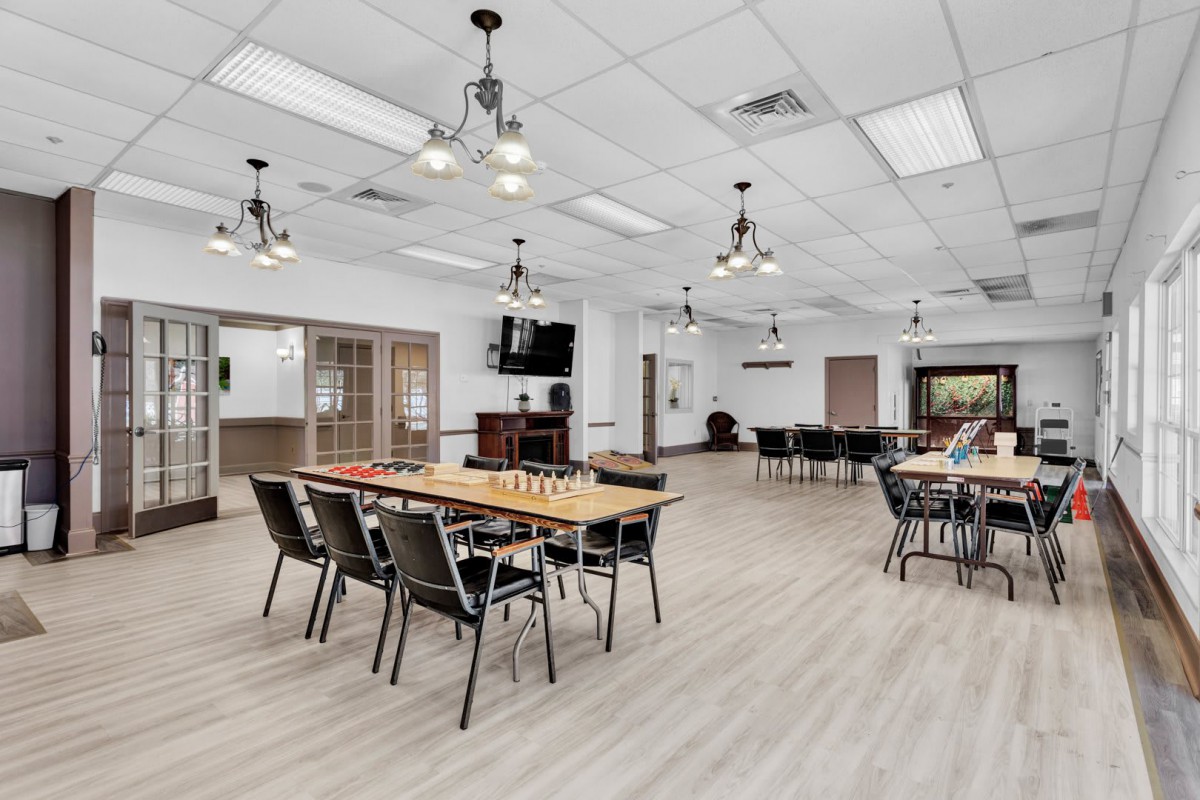 A modern dining area with tables and chairs arranged in an open space, featuring contemporary lighting fixtures.