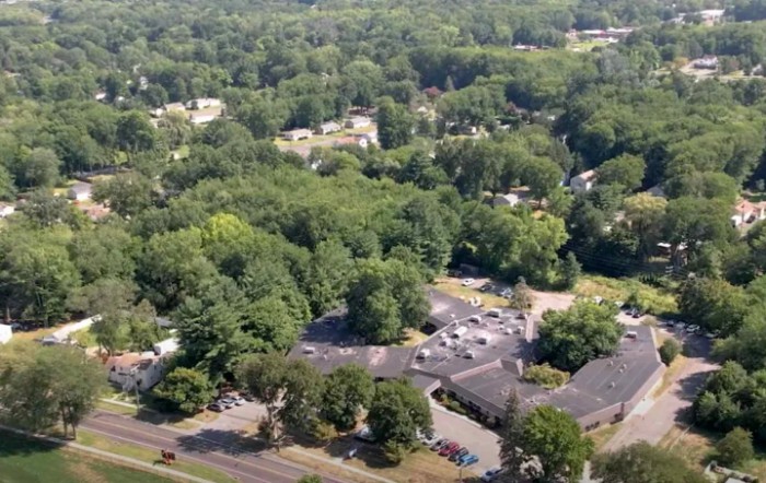 Aerial view of a suburban area with dense trees and buildings.