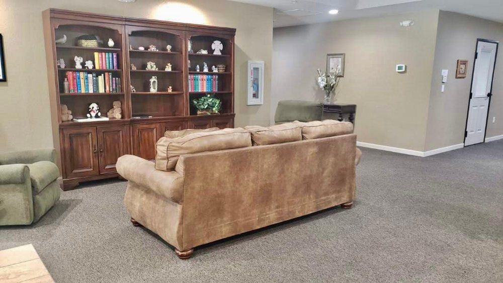 A cozy living room featuring a large beige sofa and a wooden bookshelf filled with decor items.