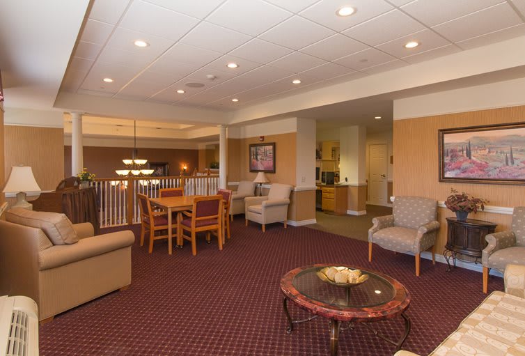 A comfortable seating area in a lobby featuring various chairs and tables under ceiling lights.