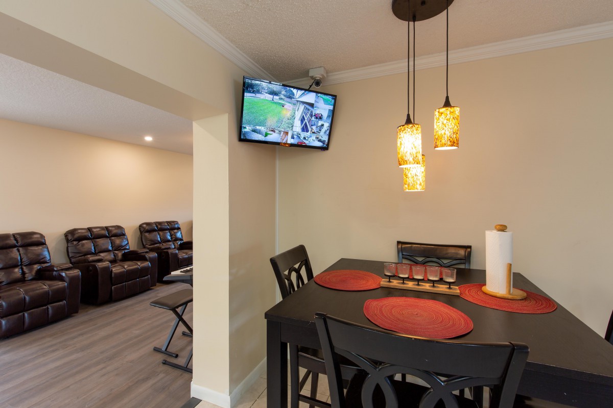 A cozy dining area with a wall-mounted TV and pendant lighting, featuring a table set with red placemats.