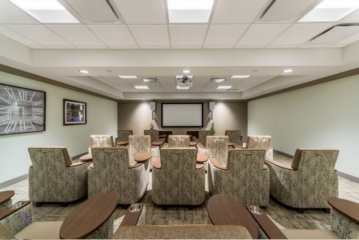 A modern conference room with comfortable seating and a projector screen for presentations.