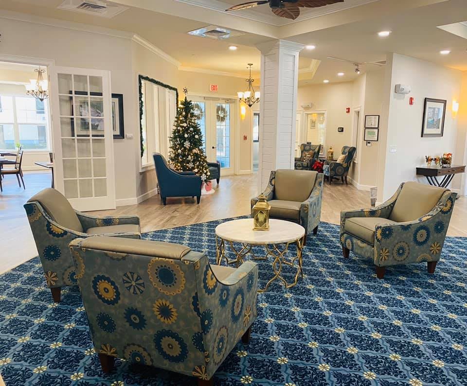A cozy lobby seating area with patterned chairs and a table, featuring a decorative carpet and festive decorations.