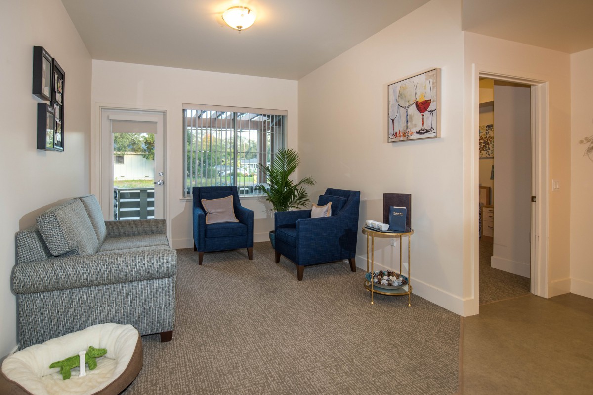 A cozy living room with armchairs and a sofa, featuring tasteful decor and soft lighting.