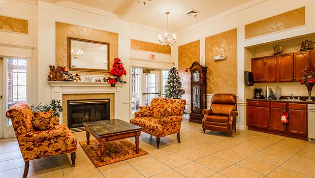A cozy living room with elegant decor, featuring a fireplace, armchairs, and a Christmas tree.
