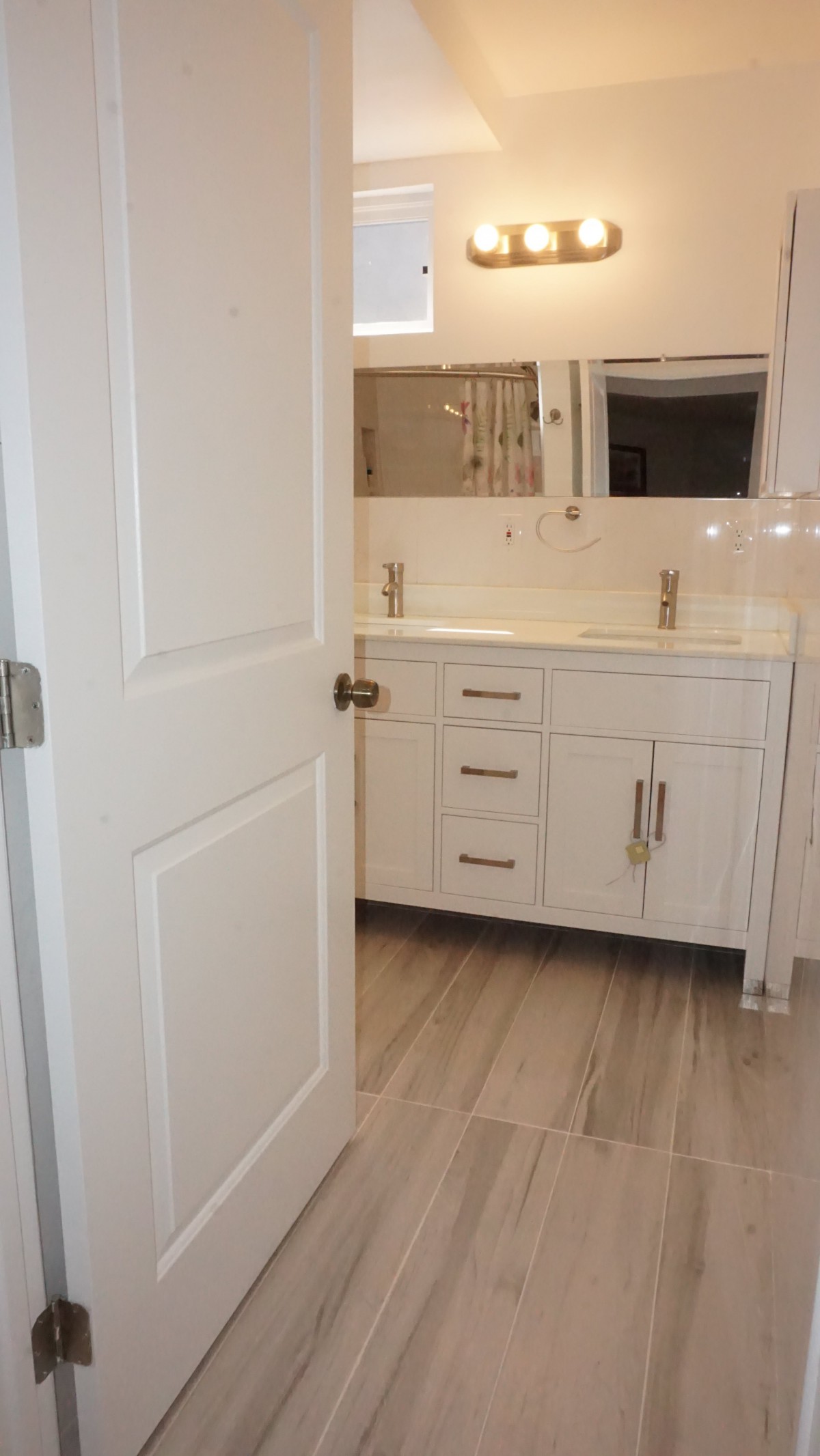 A modern bathroom features a sleek white vanity with a large mirror.
