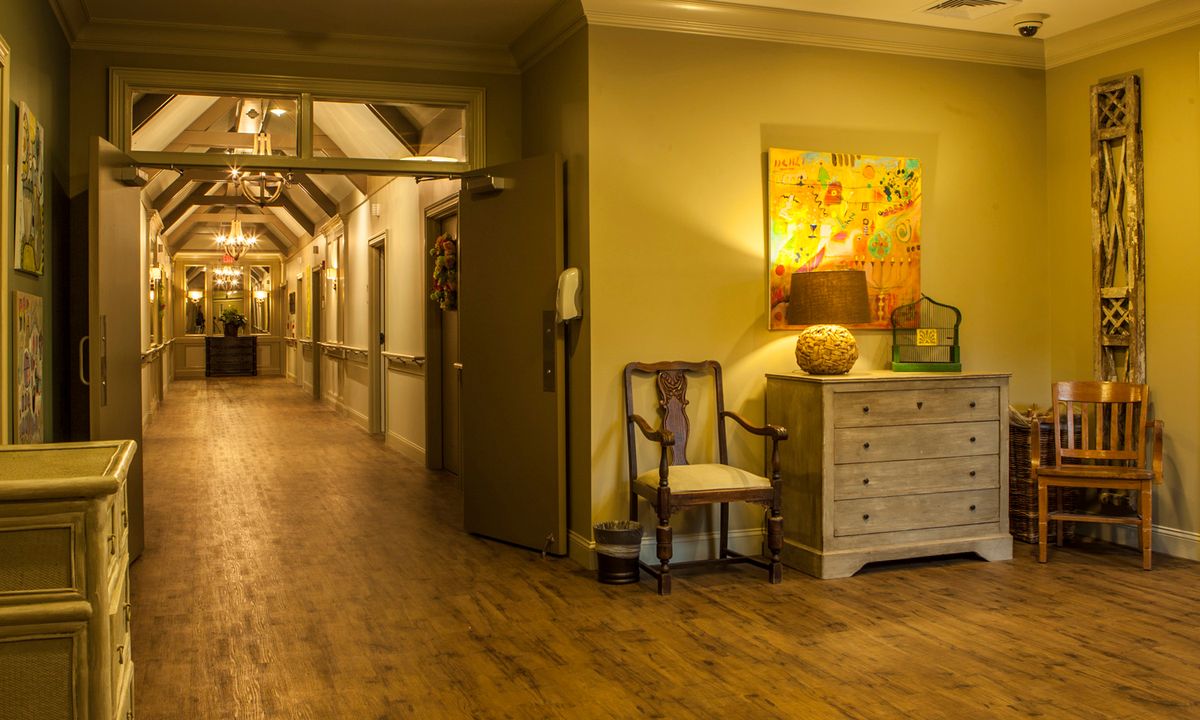A warm and inviting hallway with wooden floors, elegant furniture, and vibrant artwork on the wall.