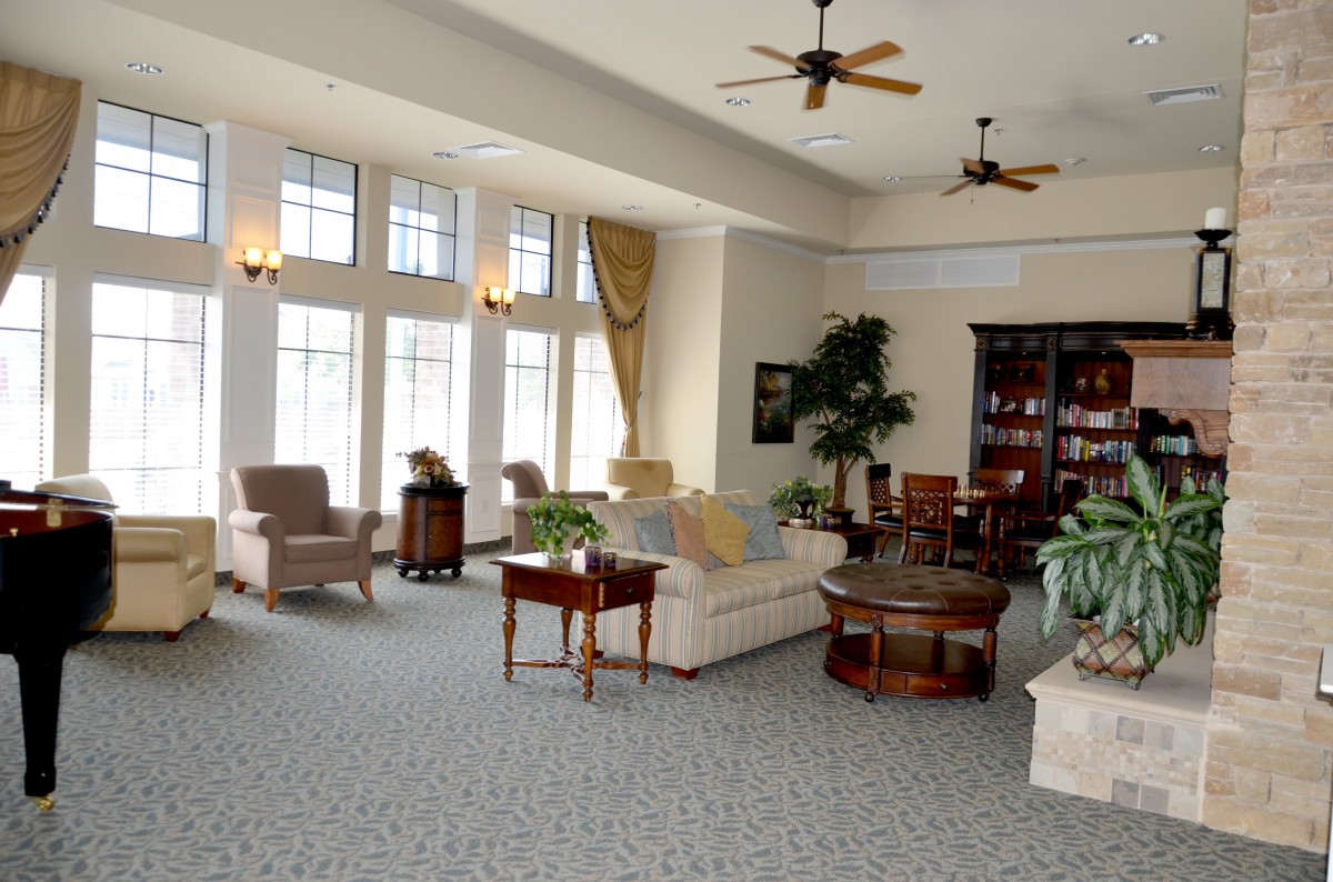 A spacious and elegantly furnished living room with large windows, multiple seating areas, and tasteful decor.