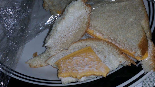 A close-up of a sandwich with cheese between slices of bread, some pieces appear to be taken out.
