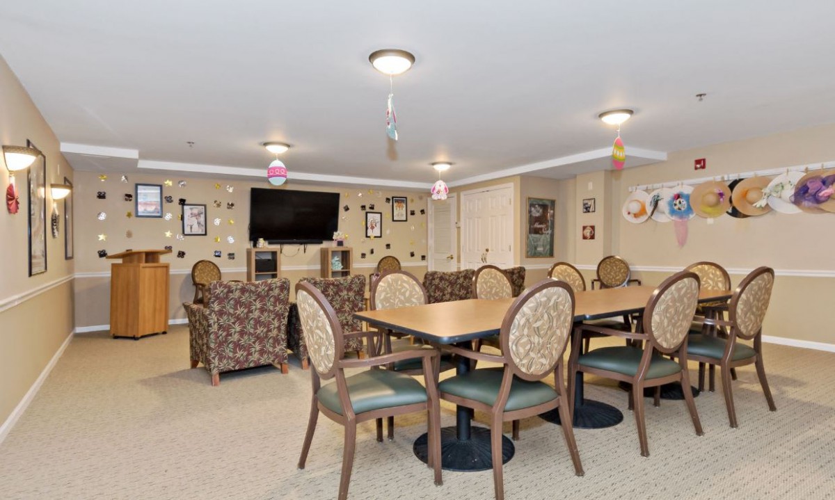 A cozy living and dining area with tables, chairs, a television, and wall decorations.
