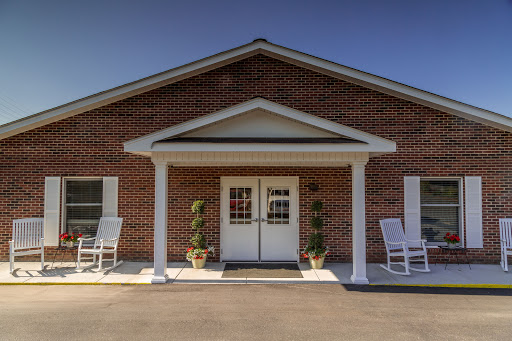 A welcoming entrance to a brick building with rocking chairs on the porch.