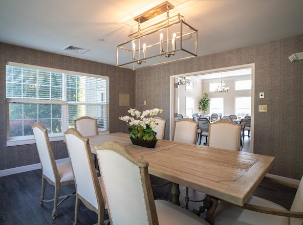 A stylish dining room with a wooden table, elegant chairs, and a modern chandelier.