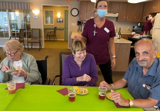Residents enjoying snacks during a social gathering with staff in a communal dining area.