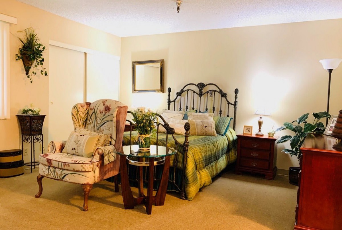 A cozy bedroom with a metal bed frame, an armchair, and ambient lighting.
