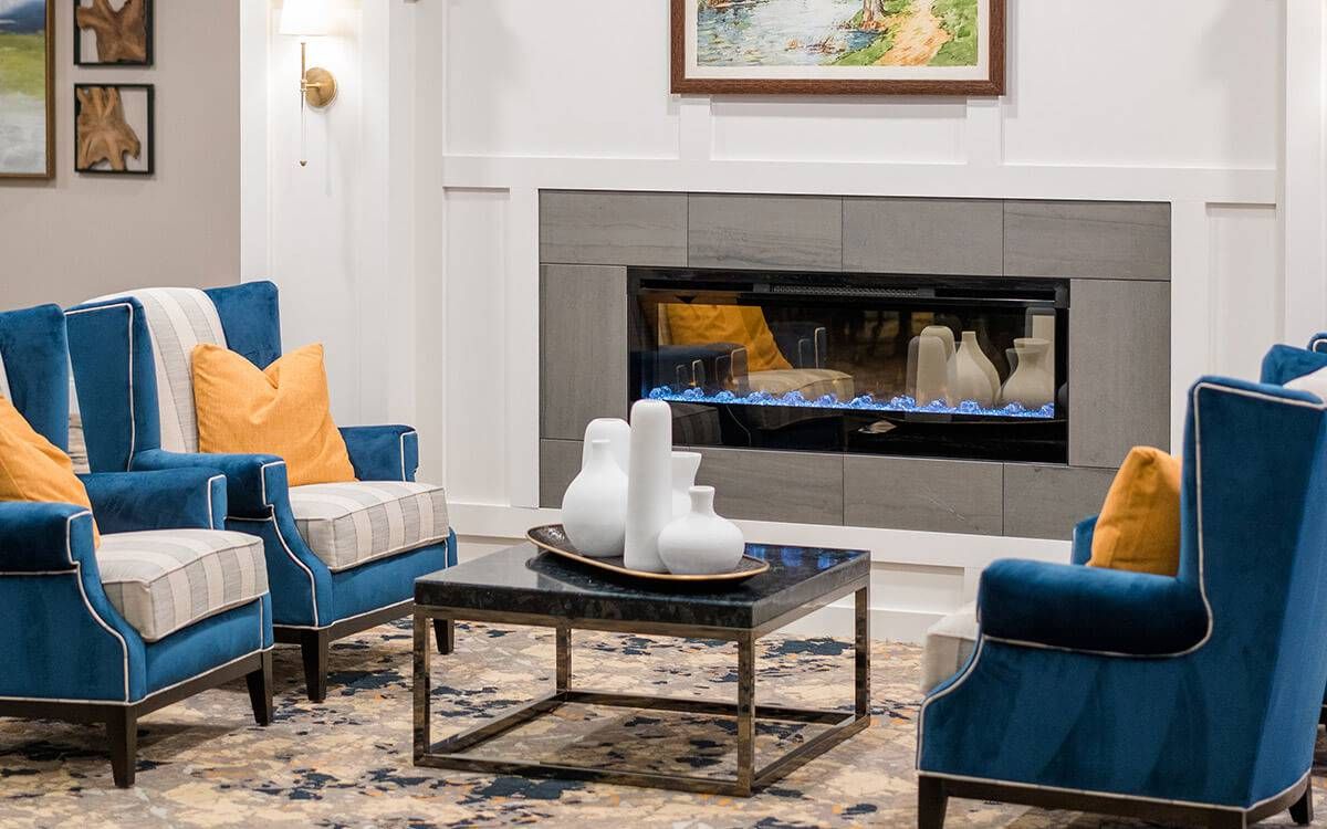 A modern living room with blue chairs and a fireplace, featuring stylish decor.