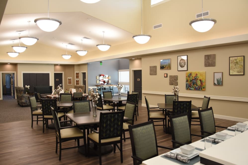 A well-lit dining area with neatly arranged tables and chairs, adorned with wall decorations.