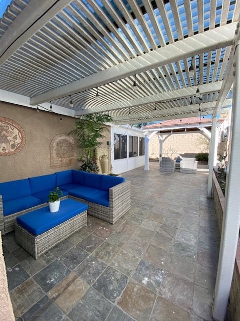 A cozy outdoor patio with blue-cushioned seating under a pergola.